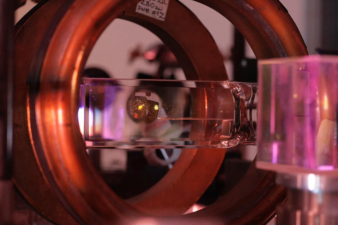 Soğuk atom düzeneğinin cam vakum hücresinde sarımsı bir atom bulutu ışıyor
