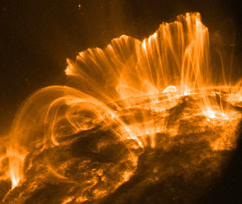 NASA'nın TRACE teleskobunun aşırı morötesi ışıkta çektiği karede Güneş'teki bir etkin bölgenin üzerinde yükselen korona ilmekleri